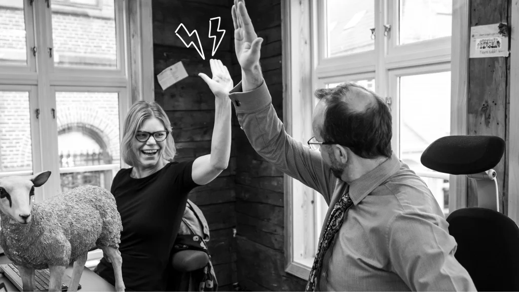 Two happy colleagues doing a perfect high five in the office